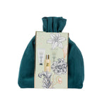 Grace & Gild Royal Lily & Vanilla body care gift set presented in a plush deep teal drawstring pouch. The pale green floral sleeve features lily artwork and images of the coordinating products.