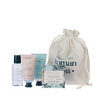 Grace & Gild Roman Spa Mini Travel Gift Set contents displayed with cream drawstring bag, including body wash, body scrub, hand cream and bath soap.