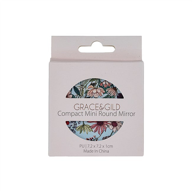 Grace & Gild compact mini round mirror in its original packaging, featuring a floral patterned mirror visible through a circular cutout on a light pink box.