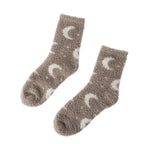 A pair of fuzzy crew socks in taupe brown with a white crescent moon and star pattern, displayed on a clean white background.