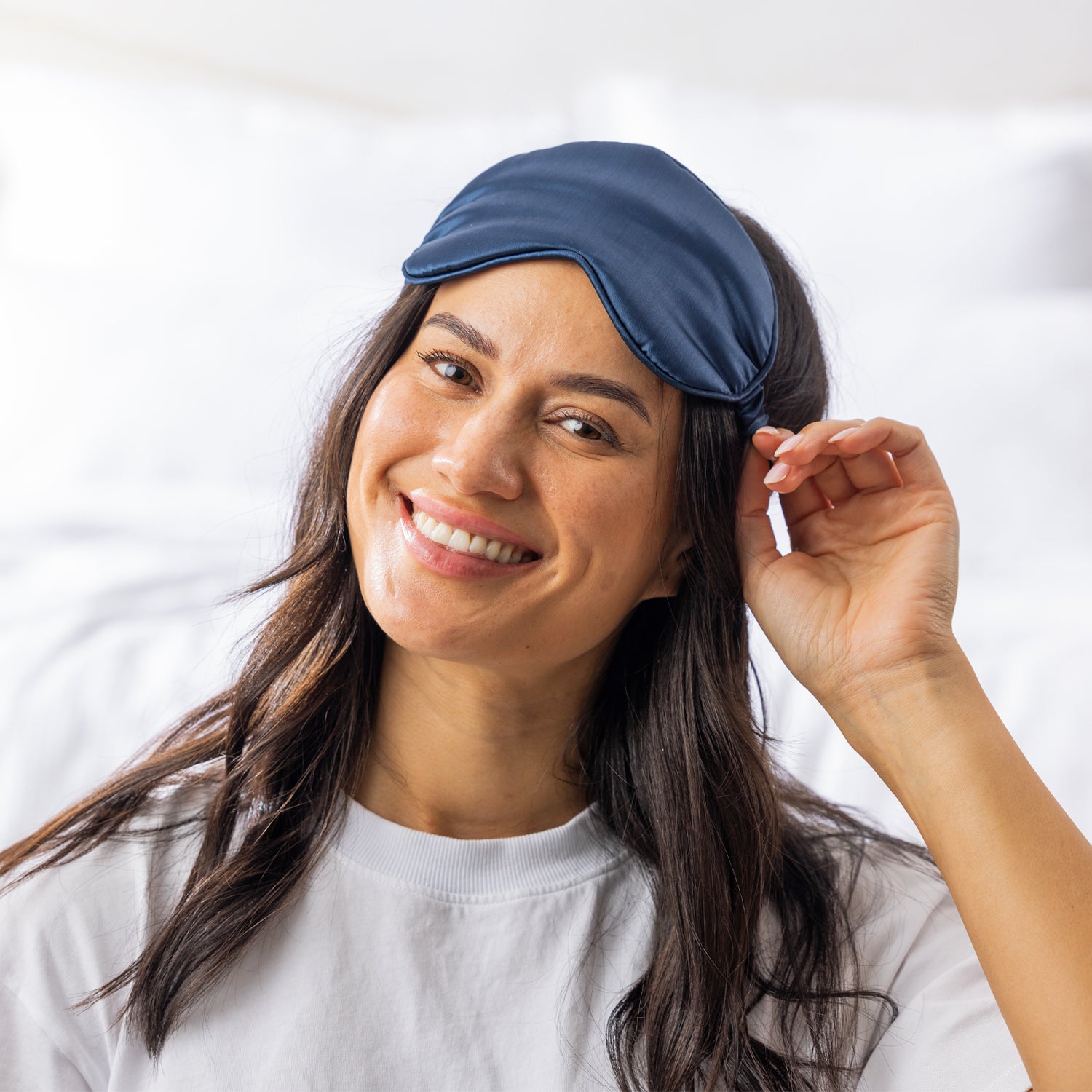 Woman wearing the Grace & Gild So Soft Navy Eye Mask in a bright bedroom setting.