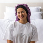 Woman wearing the Grace & Gild Long Sleep Bonnet in mauve with a wide black band.