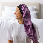 Side view of a woman wearing the mauve Grace & Gild Long Sleep Bonnet with a black band.