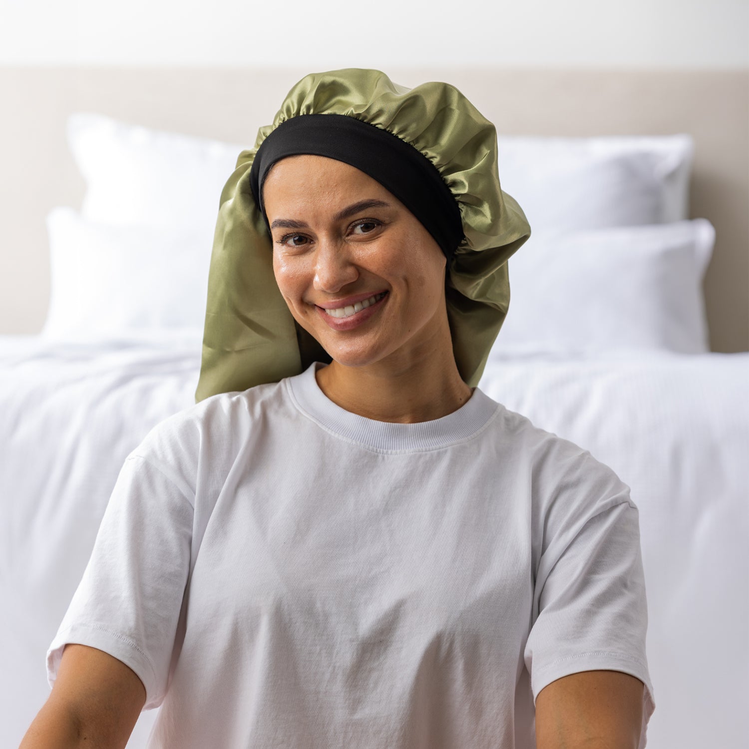 Woman wearing the Grace & Gild Long Sleep Bonnet in green with a wide black band.