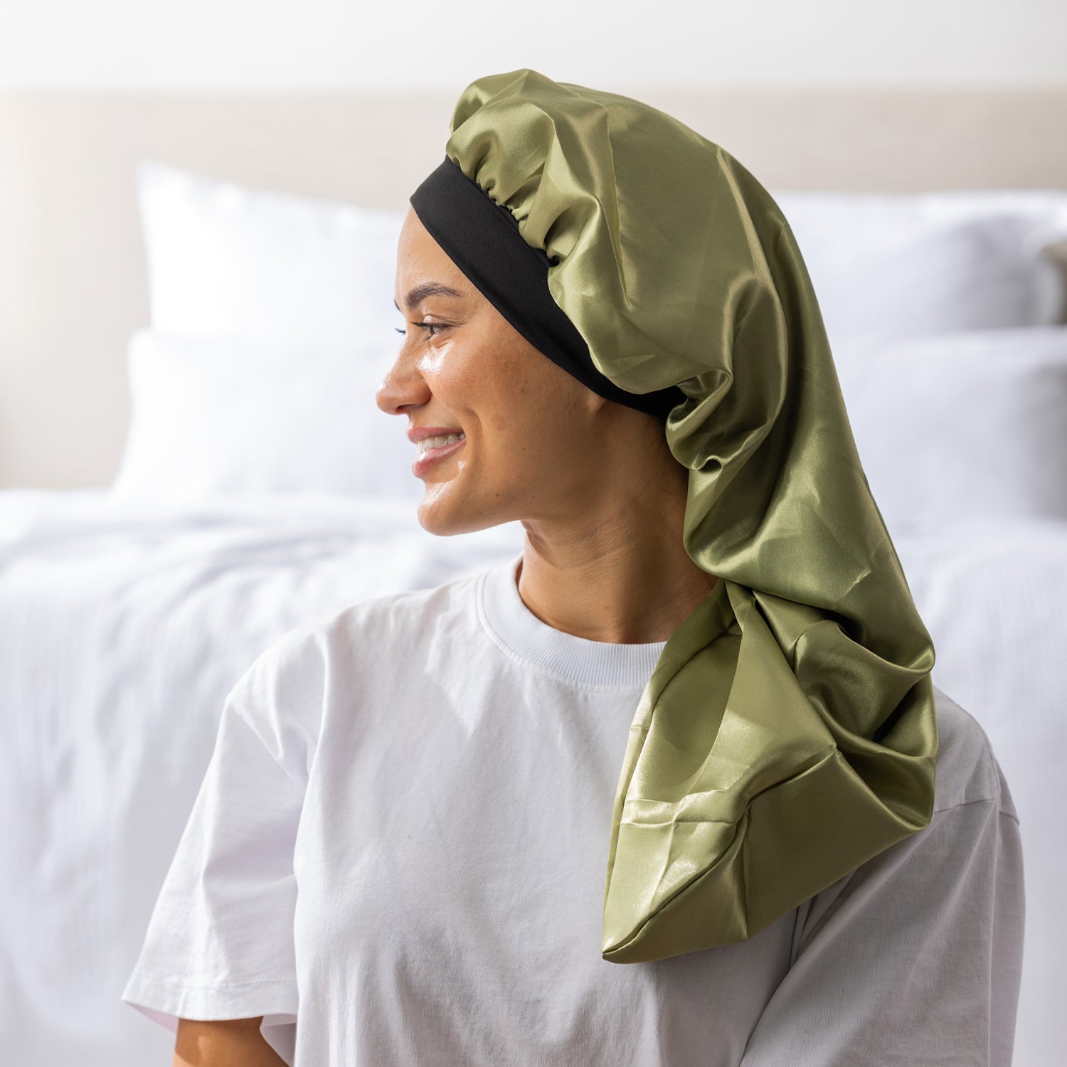 Side view of a woman wearing the green Grace & Gild Long Sleep Bonnet with a black band.