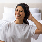 Woman adjusting the dark brown Grace & Gild Long Sleep Bonnet with a wide black band.