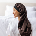 Side view of a woman wearing the dark brown Grace & Gild Long Sleep Bonnet with a black band.