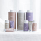 Eden scented talcum powder and hand cream range arranged together in Rose, Gardenia and Orchid fragrances, featuring coordinating pastel packaging on a white fabric surface.