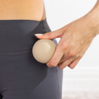 Close-up of a natural-coloured massage ball held against the hip area.