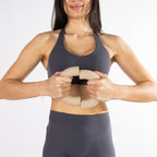 Woman holding two natural-coloured curved dumbbells together in front of her torso during a fitness exercise.