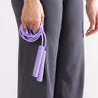 Close-up of a purple skipping rope with textured handles held in one hand.