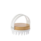 Grace & Gild Emmy Massage Body Brush shown from the back, featuring a round bamboo base, flexible white hand strap and silicone massage bristles.