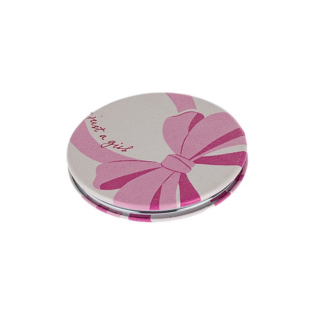 A round compact mirror featuring a pink and magenta bow design on a light gray background, with the cursive text 'Just a girl' printed on the lid.