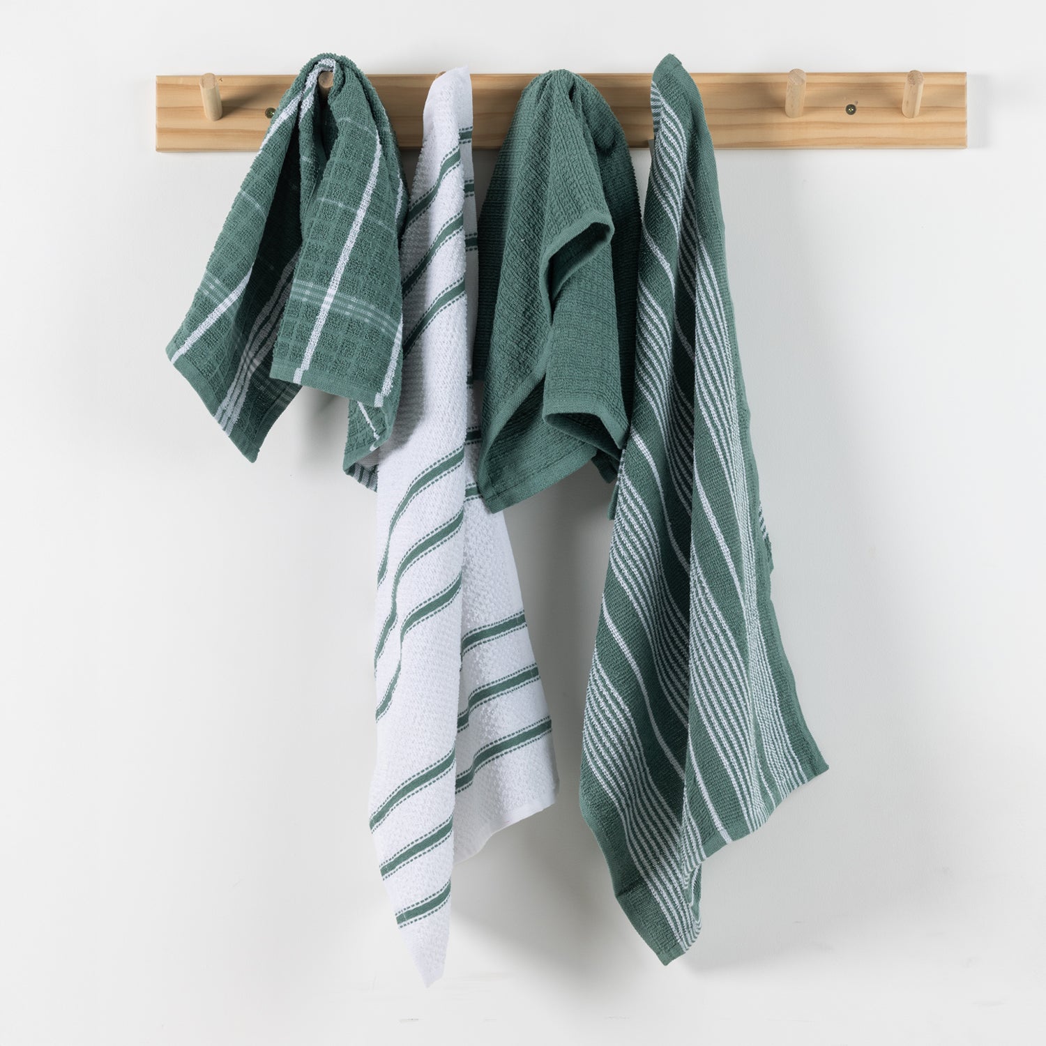 Home Co. Terry Tea Towels 4 Pack in Sage, shown hanging on a wooden wall rack with coordinating check, stripe, and plain sage designs.