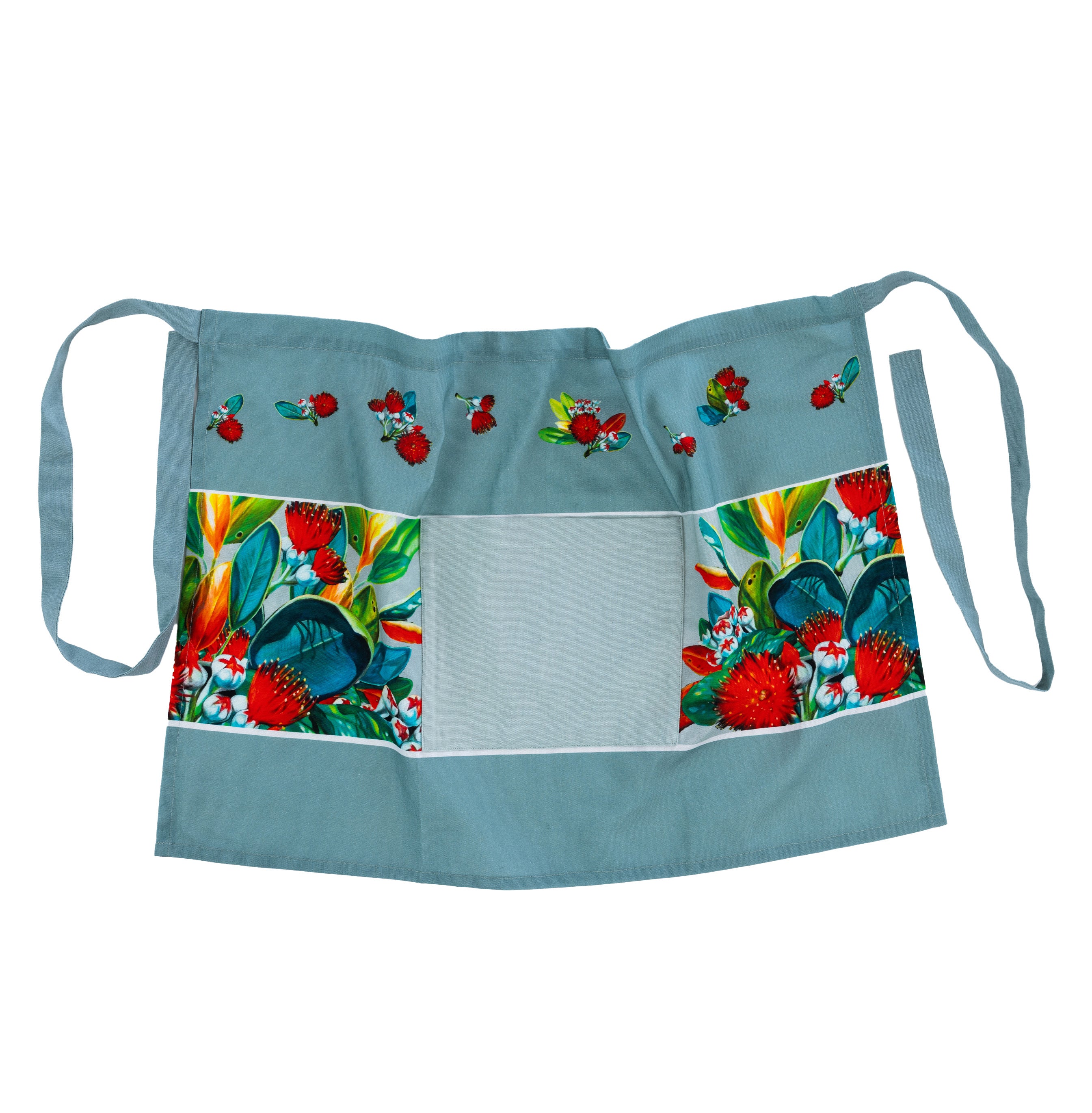 Design Plus Kiwiana Pohutukawa Half Apron featuring a soft sage green background with vibrant pōhutukawa floral panels, scattered floral motifs, a large front pocket and adjustable waist ties.