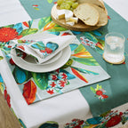 Two Design Plus Kiwiana Pohutukawa napkins styled on a coordinated table setting with matching placemats, table runner and tablecloth, featuring bold red pōhutukawa blooms and green foliage.