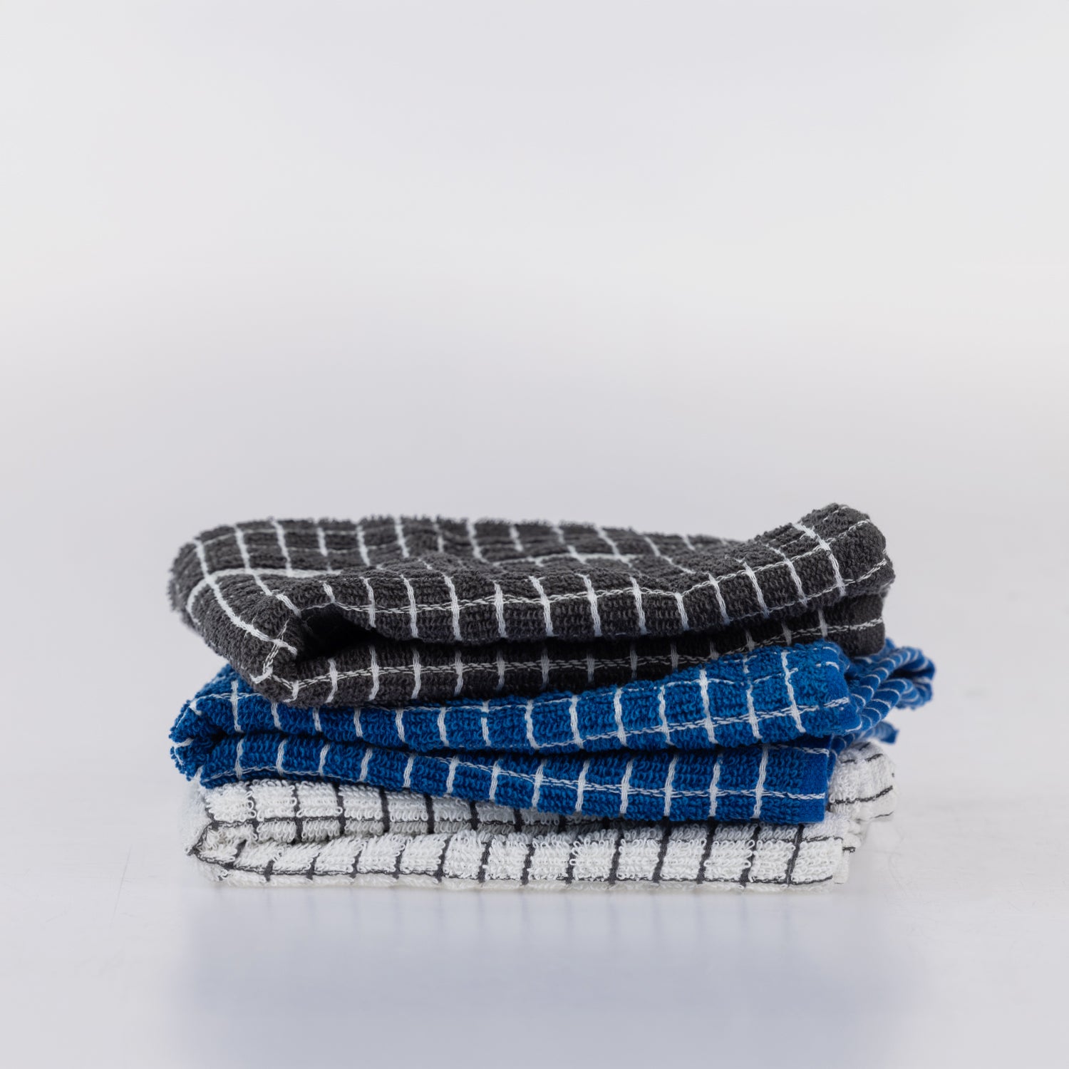 A stack of three folded kitchen towels with a textured waffle-weave pattern.