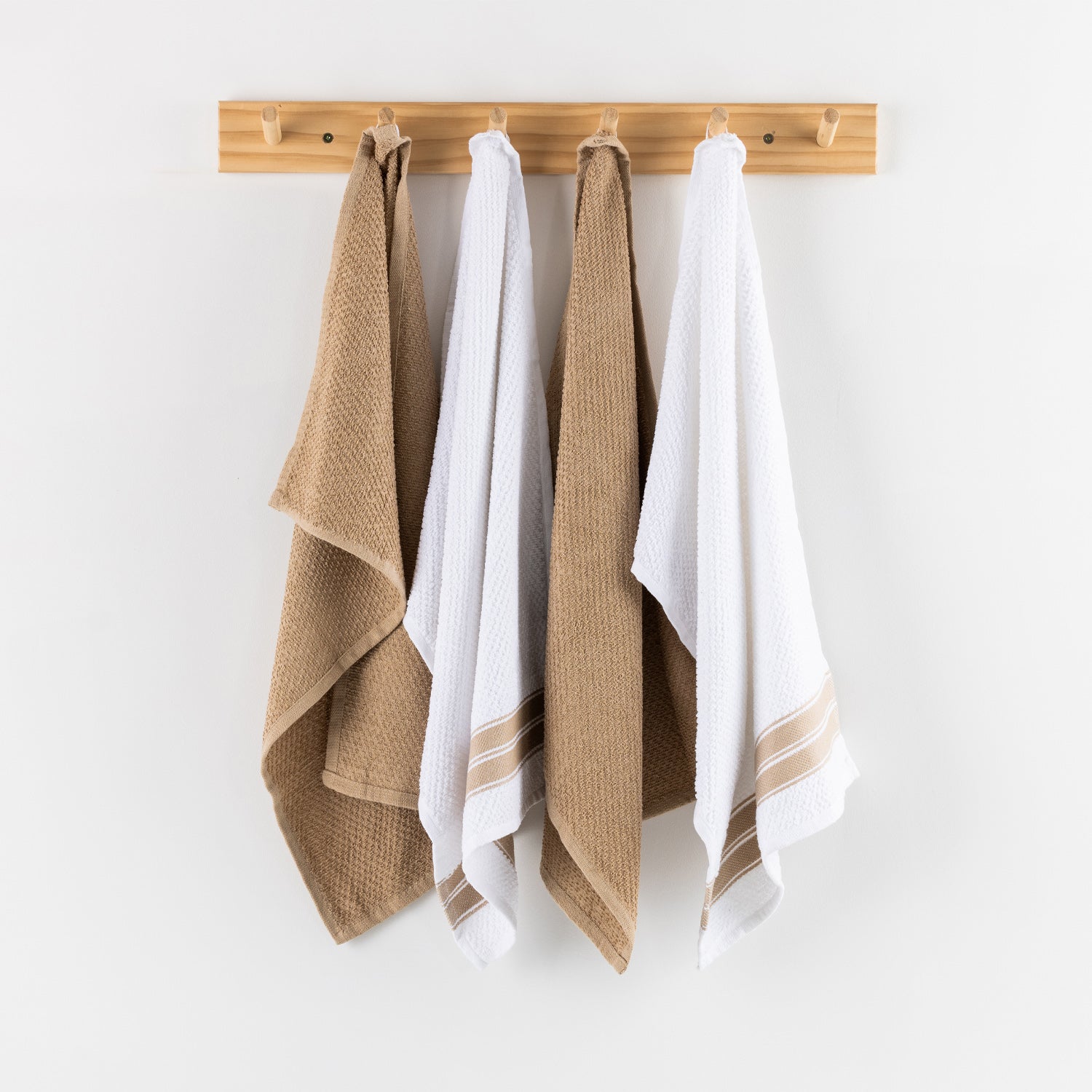 A set of four textured tea towels in alternating white and natural beige tones hangs neatly from a light timber wall rack, creating a clean and inviting kitchen display.