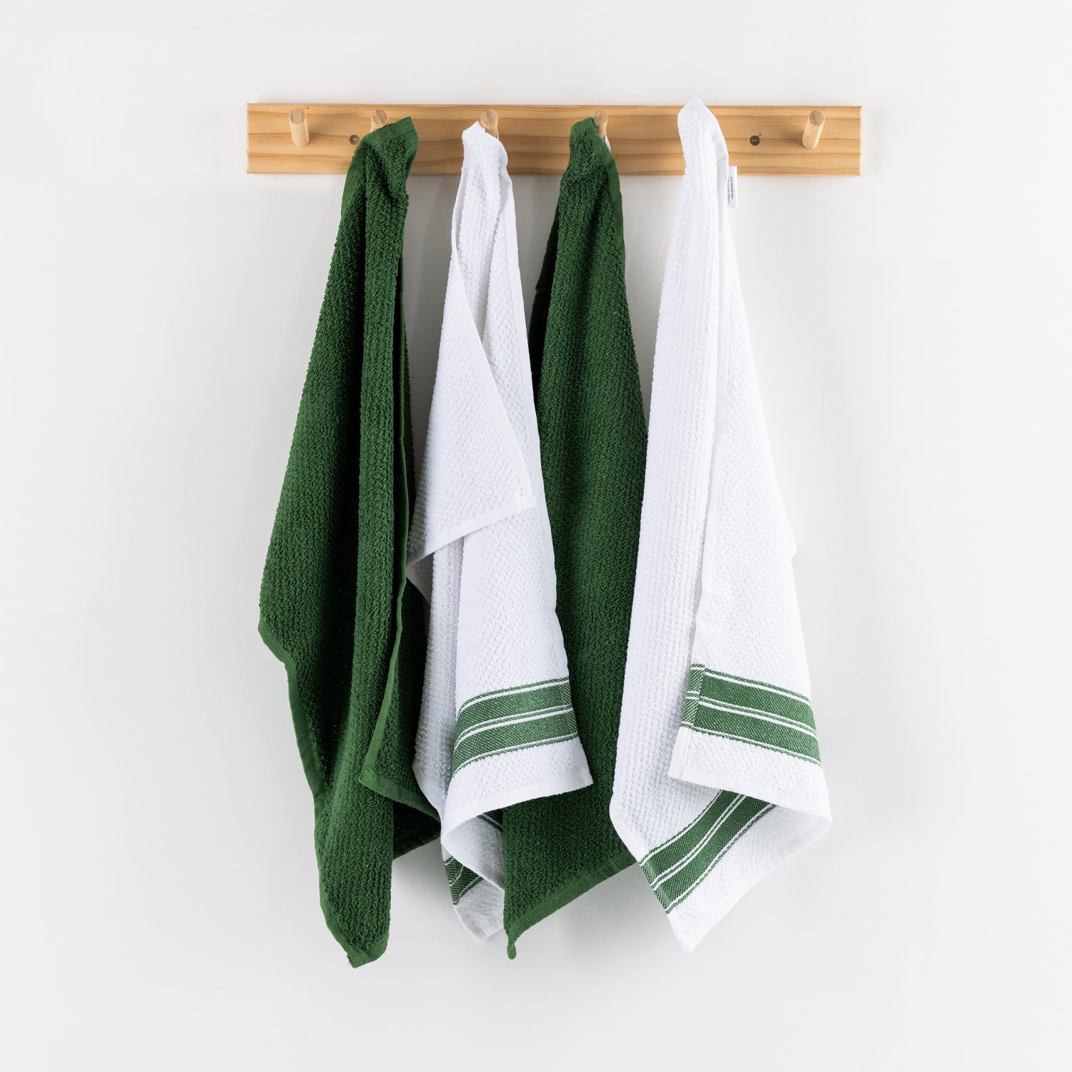 A set of four textured tea towels in alternating white and green tones hangs neatly from a light timber wall rack, creating a clean and inviting kitchen display.