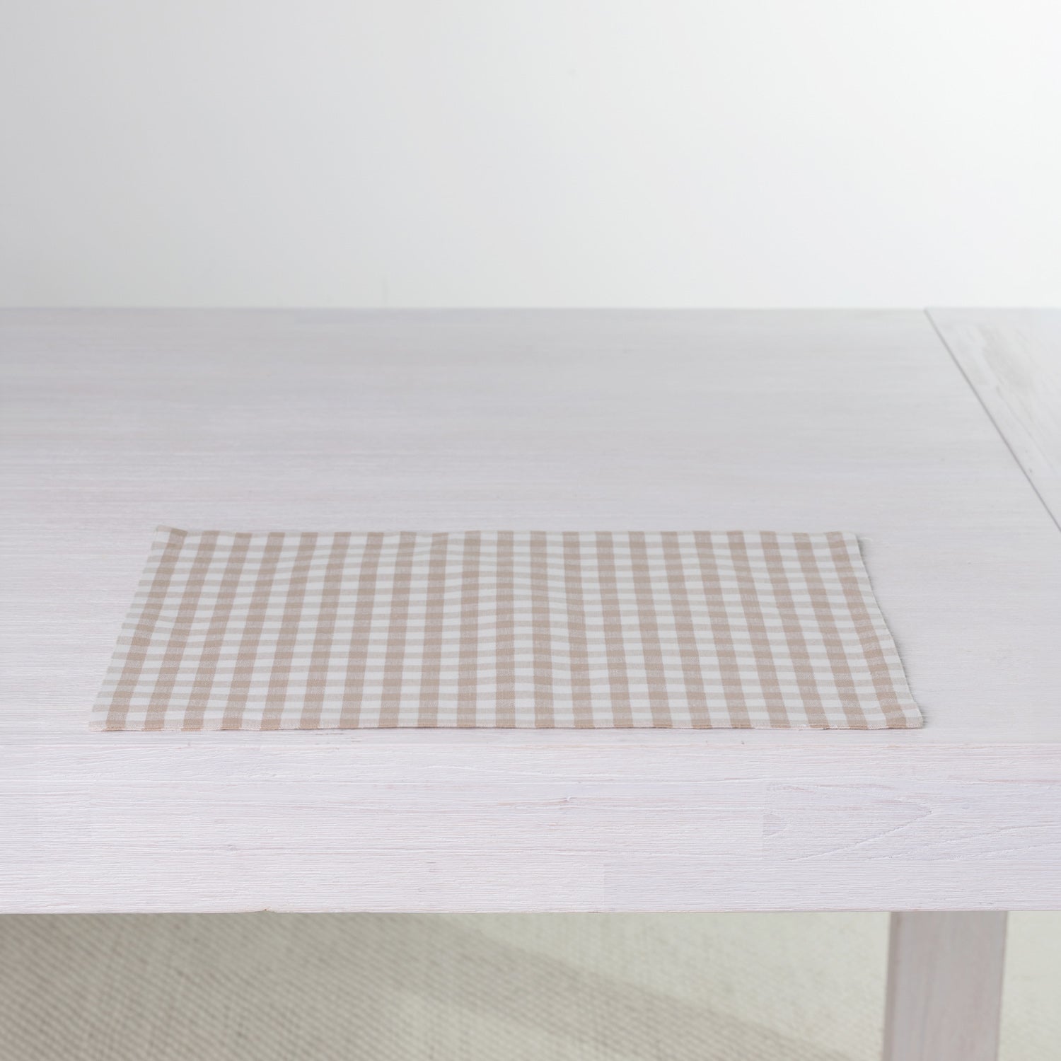 Gather Vichy Checks fused placemat in Brown/Cream laid flat on a white dining table.