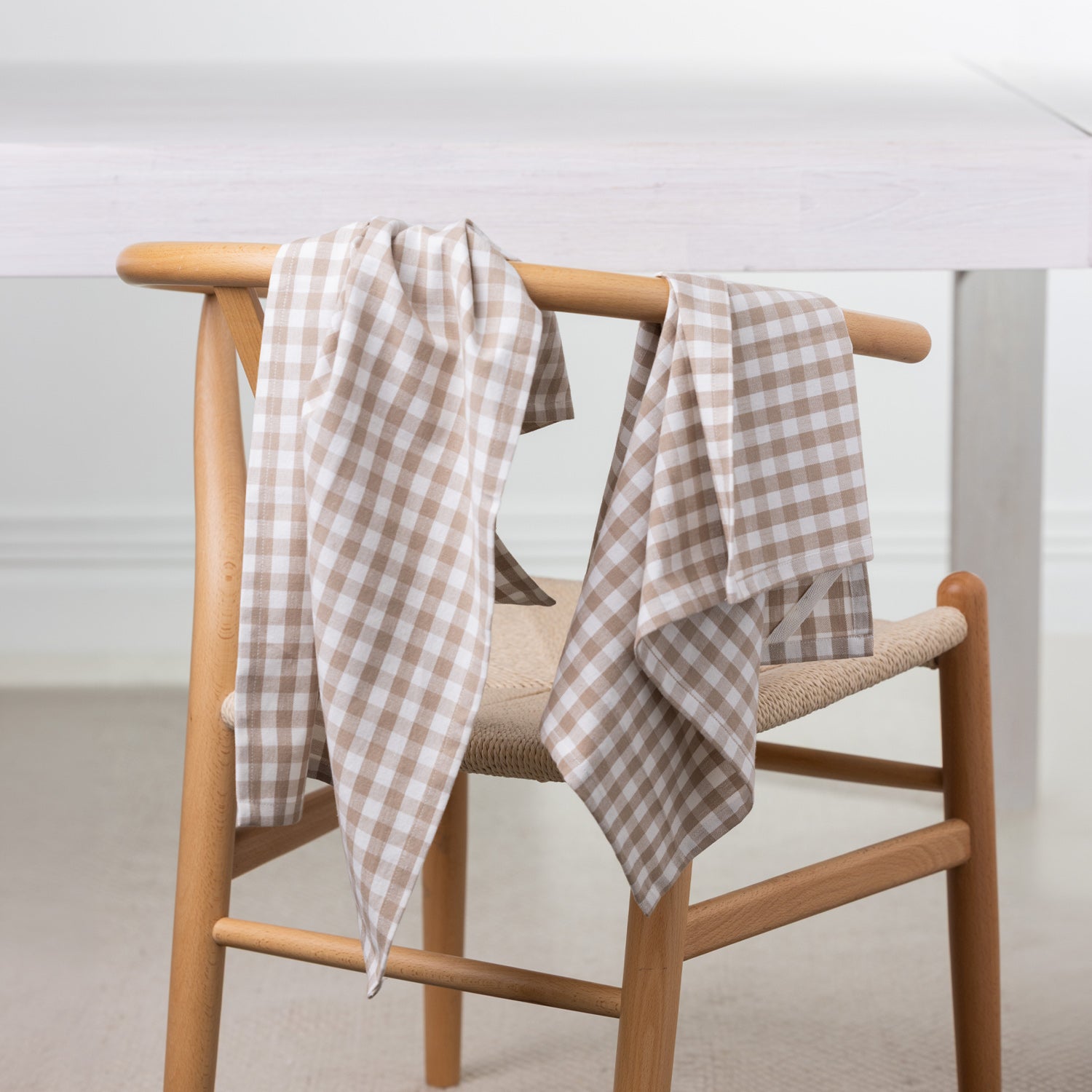 Gather Vichy Checks tea towels in Brown/Cream draped over the back of a wooden dining chair.