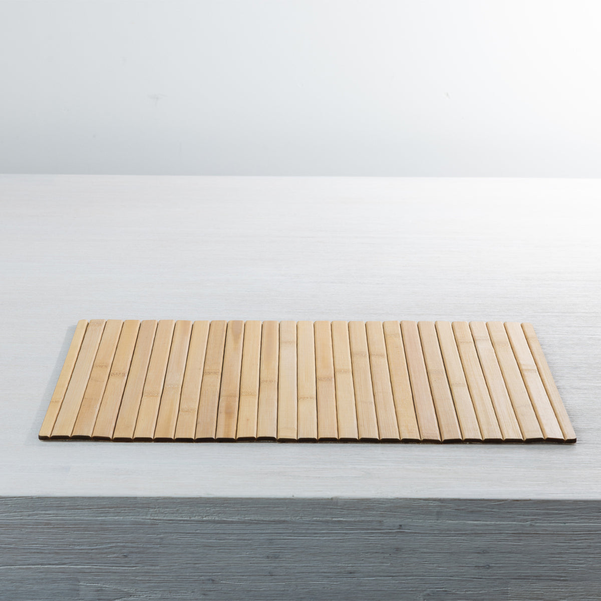 Gather Bamboo Placemat in Natural, showcasing its rectangular shape, smooth bamboo slats and warm natural tones on a white dining table.