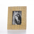 A rectangular picture frame with a textured, woven-like pattern in beige and brown tones, holding a black and white portrait of a woman.