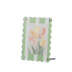 Green scalloped-edge photo frame with a striped green and white design, silver corner fasteners and a floral print displayed inside, shown on a white background.