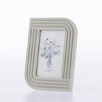 A light gray rectangular picture frame with rounded top corners and horizontal ridged detailing, holding a white insert with a blue floral illustration. The frame is photographed on a clean white background.