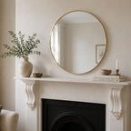 Round gold aluminium mirror styled above a fireplace mantel in a neutral living room.