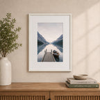 A white wood-look photo frame with a wide white mat beautifully showcases a tranquil lakeside landscape, styled above a timber sideboard in a warm, contemporary interior.