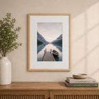 A natural wood-look photo frame with a wide white mat beautifully showcases a tranquil lakeside landscape, styled above a timber sideboard in a warm, contemporary interior.