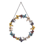 Round wall mirror surrounded by multicoloured decorative butterflies with a metal hanging chain.