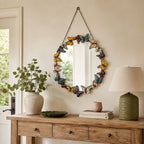 Round wall mirror with a multicoloured butterfly frame and hanging chain, displayed above a wooden console table.
