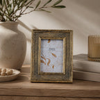 Design Republique Hess Gold Photo Frame styled on a wooden console table with neutral décor, books, a candle and ceramic vase in a warm contemporary interior.