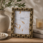 Design Republique Gold Knot Photo Frame styled on a wooden console table with a ceramic vase, candle and decorative books in a warm contemporary interior.