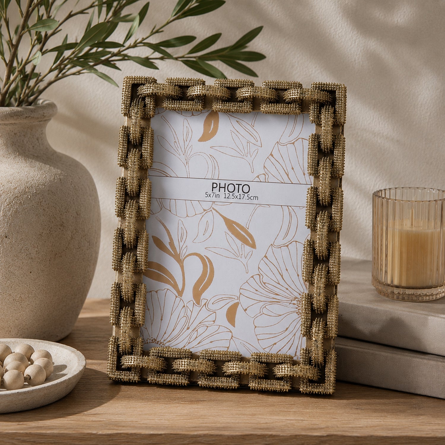 Design Republique Gold Knot Photo Frame styled on a wooden console table with a ceramic vase, candle and decorative books in a warm contemporary interior.