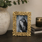 Design Republique Leaves Gold Photo Frame styled on a dark wooden console table with a ceramic vase, candle and decorative accents in a warm contemporary interior.