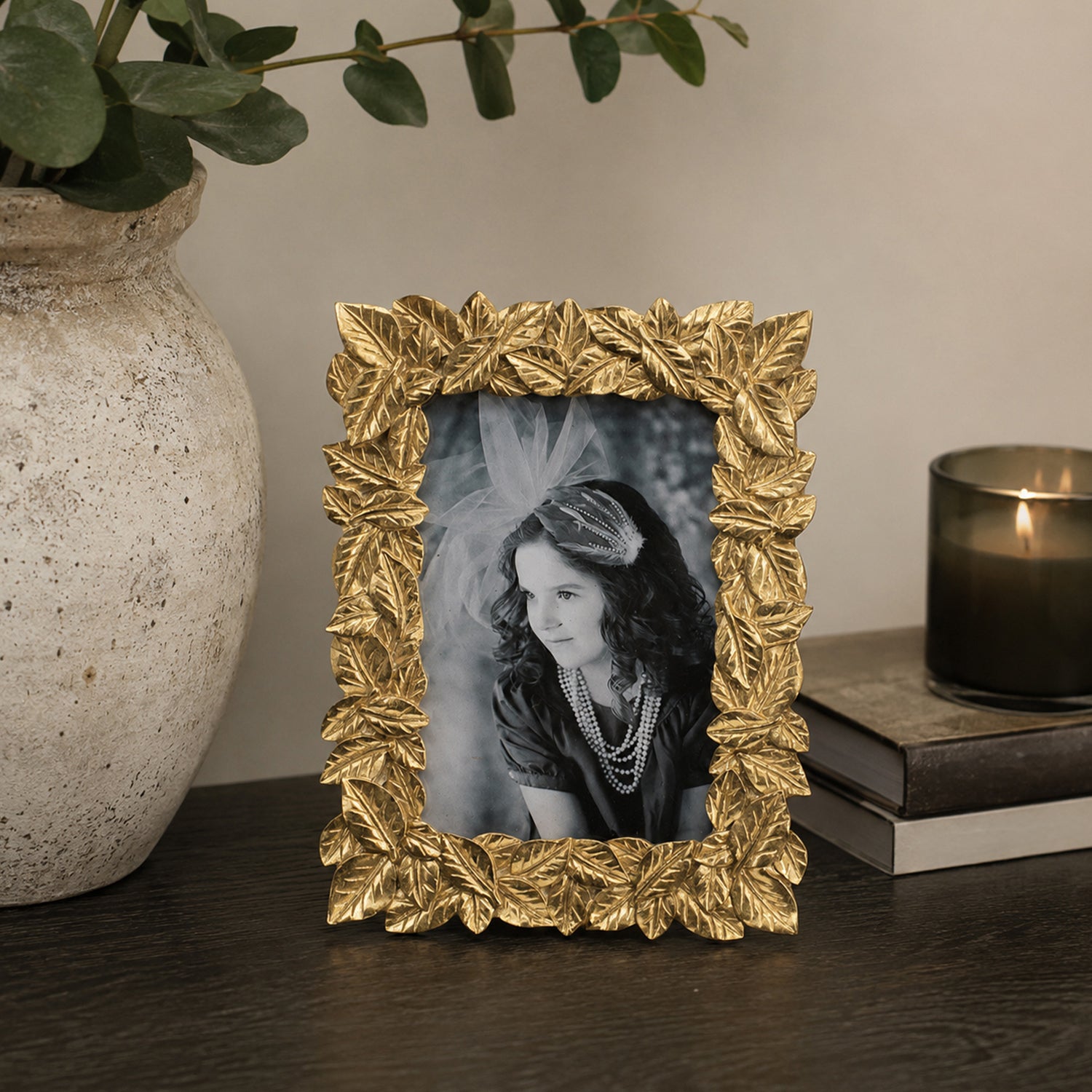 Design Republique Leaves Gold Photo Frame styled on a dark wooden console table with a ceramic vase, candle and decorative accents in a warm contemporary interior.