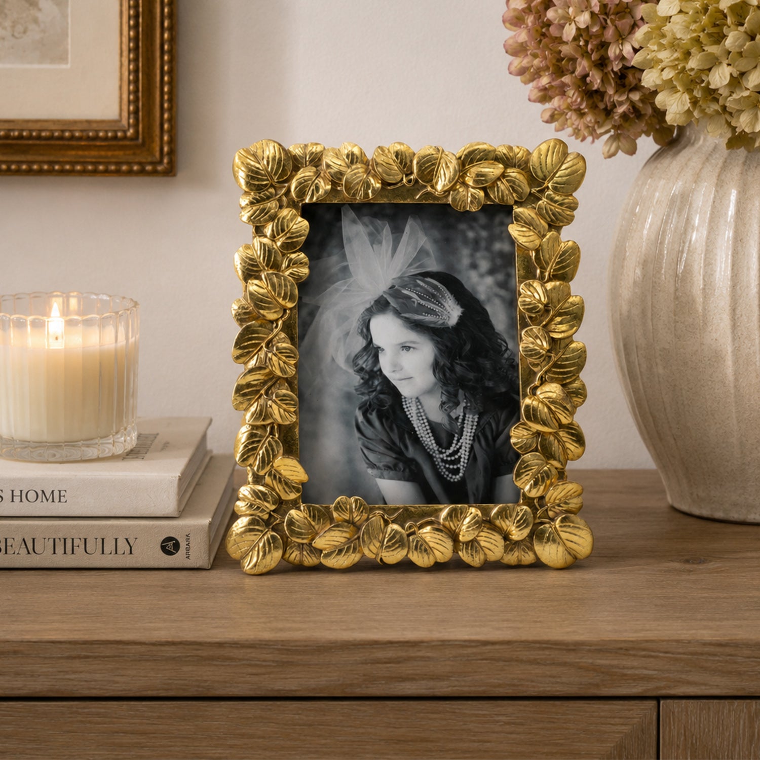 Design Republique Flora Gold Photo Frame styled on a wooden console table with books, a lit candle and ceramic vase in a warm, elegant interior.