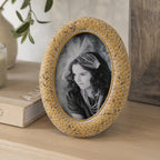 Design Republique Ella Natural Oval Photo Frame styled on a wooden console table with books, a candle and ceramic vase in a warm, natural home setting.