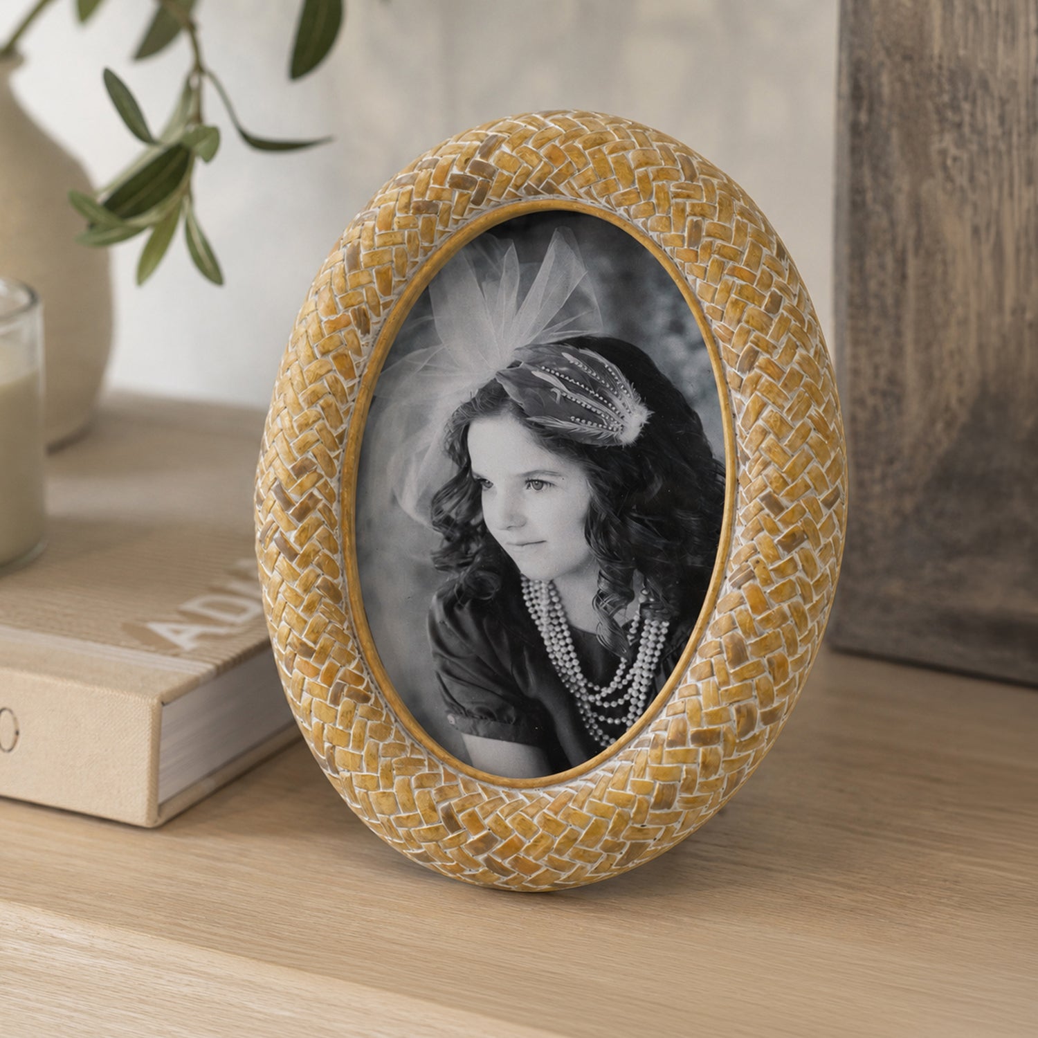 Design Republique Ella Natural Oval Photo Frame styled on a wooden console table with books, a candle and ceramic vase in a warm, natural home setting.