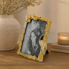 Design Republique Flamingo Large Gold Photo Frame styled on a wooden console table with a textured ceramic vase, books and a candle in a warm, elegant home setting.