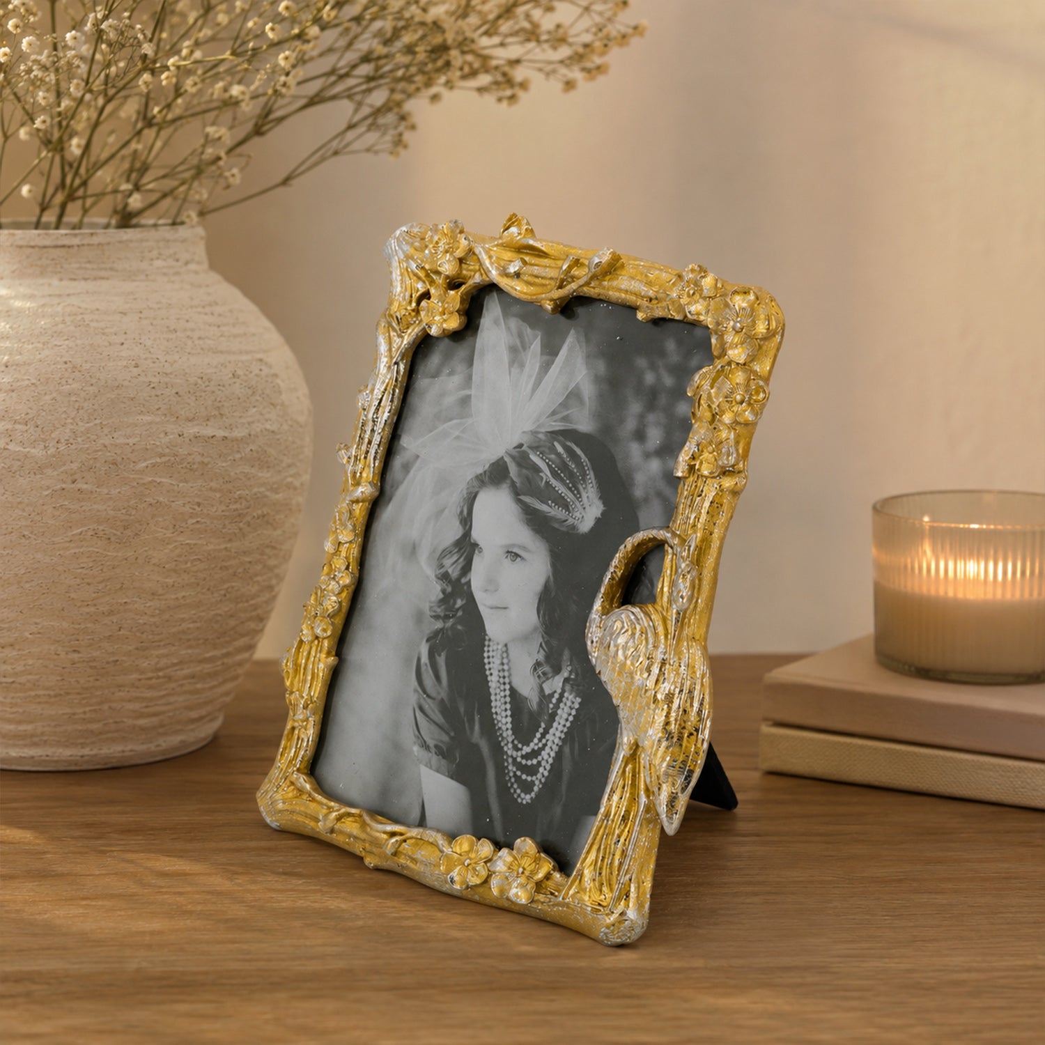 Design Republique Flamingo Large Gold Photo Frame styled on a wooden console table with a textured ceramic vase, books and a candle in a warm, elegant home setting.