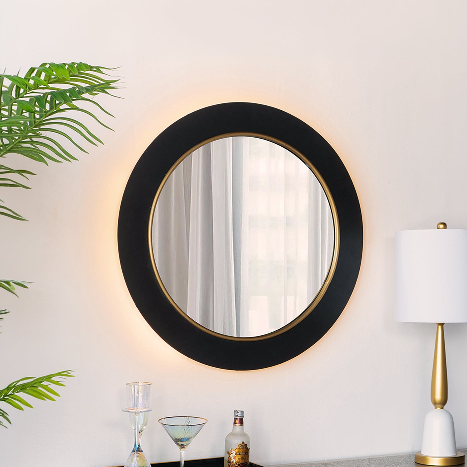 Design Plus Leona LED Mirror mounted above a console table with warm LED backlighting, styled with a lamp, greenery and decorative accessories.