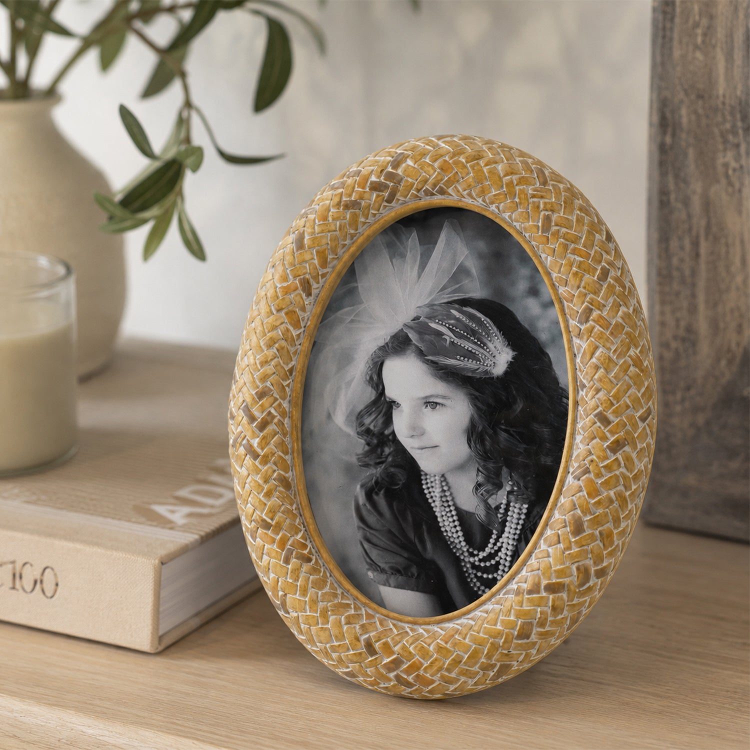 Design Republique Ella Natural Oval Photo Frame styled on a wooden console table with books, a candle and ceramic vase in a warm, natural home setting.