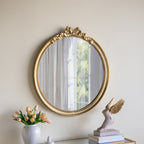 Gracious Living Bella Bow Mirror displayed on a neutral wall in a styled interior, featuring its antique gold bow and ribbon frame.