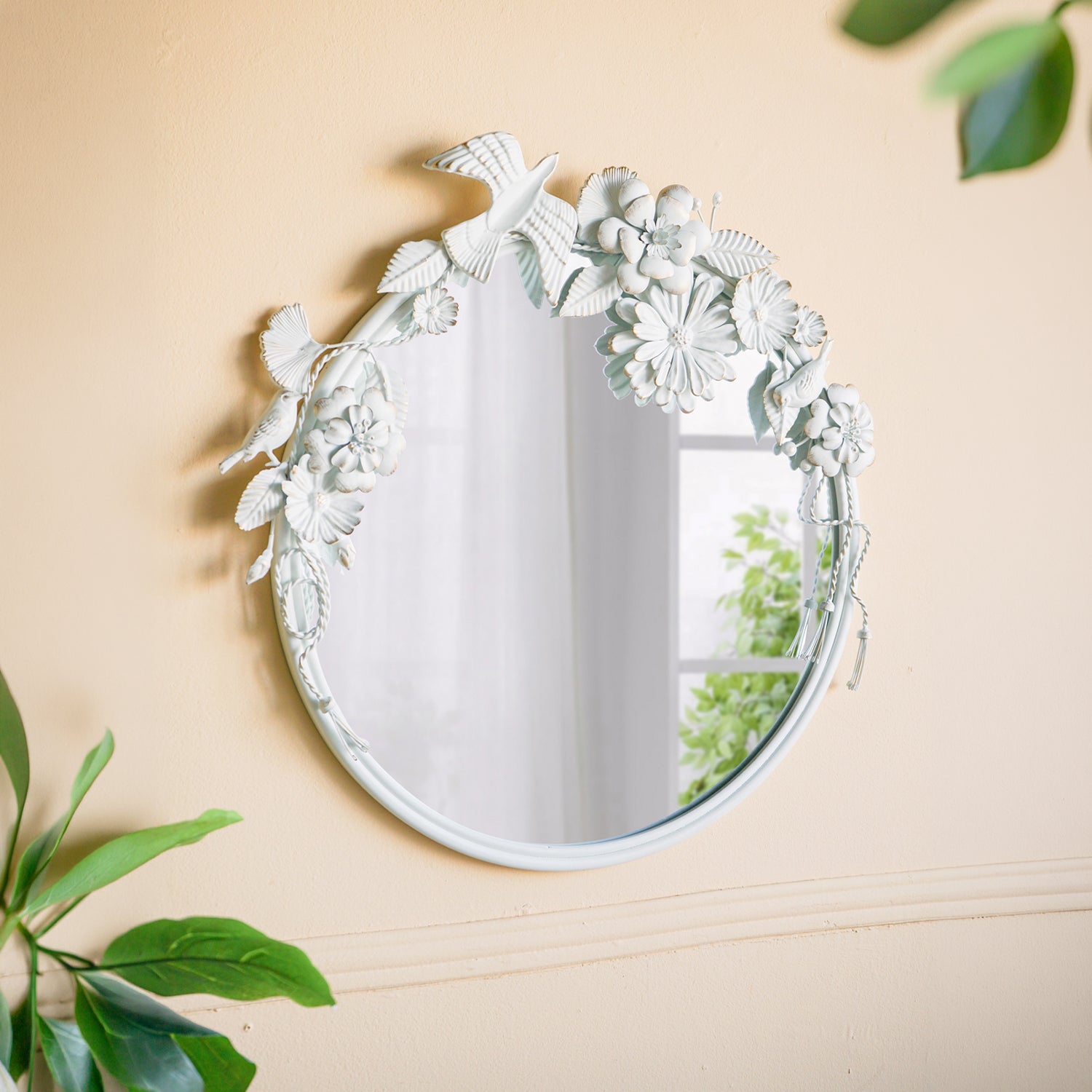 Gracious Living Birds & Flowers Round Mirror displayed on a warm neutral wall, featuring decorative white birds, flowers and leaves around the circular mirror.