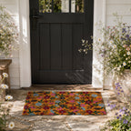 A vibrant floral coir doormat adds a warm, colourful welcome to this charming modern farmhouse entryway, framed by lush cottage-style blooms and a classic black front door.