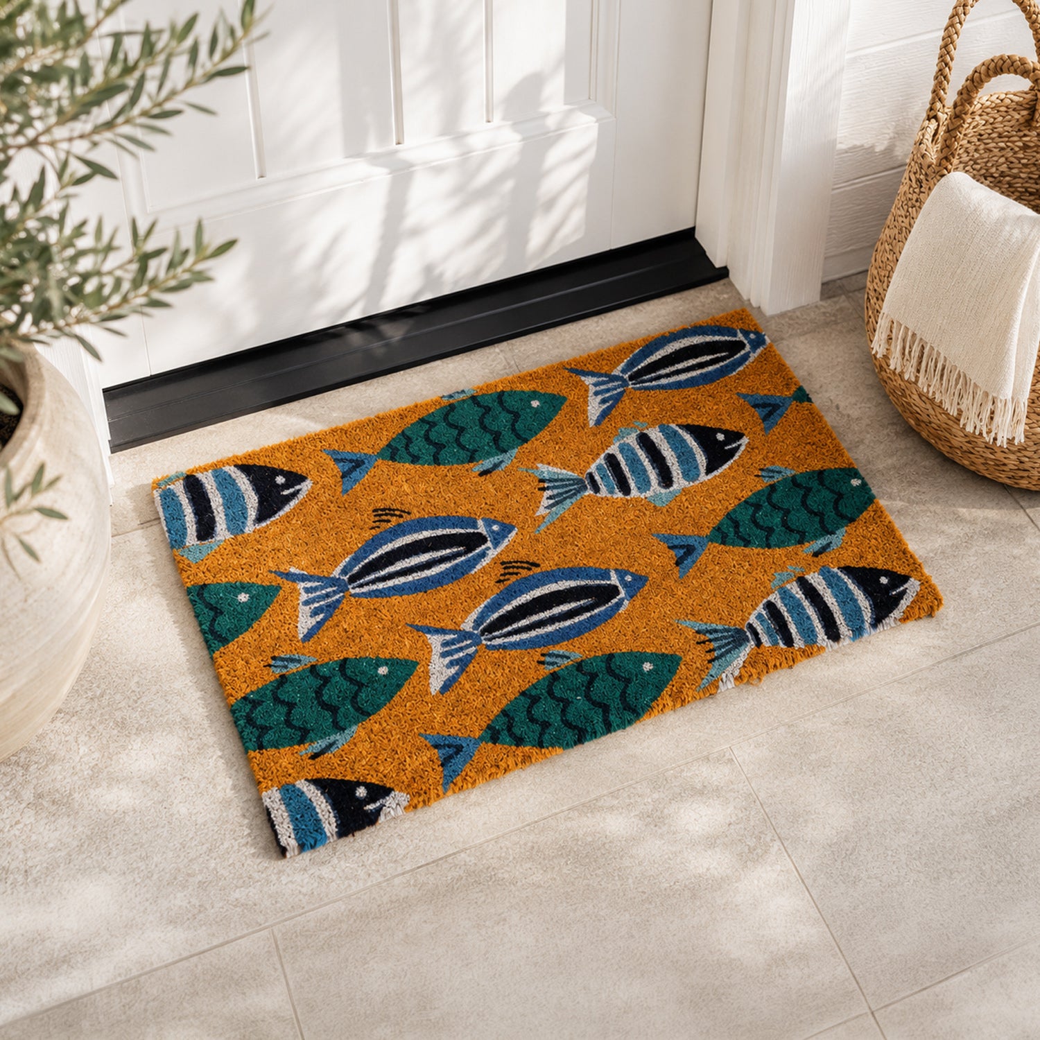 A vibrant coir doormat featuring playful blue and teal fish adds a cheerful coastal-inspired touch to a bright, welcoming entryway.